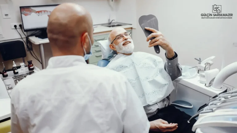 Diş kliniğinde tedavi koltuğunda oturan yaşlı bir erkek hasta elindeki aynaya gülümseyerek bakıyor